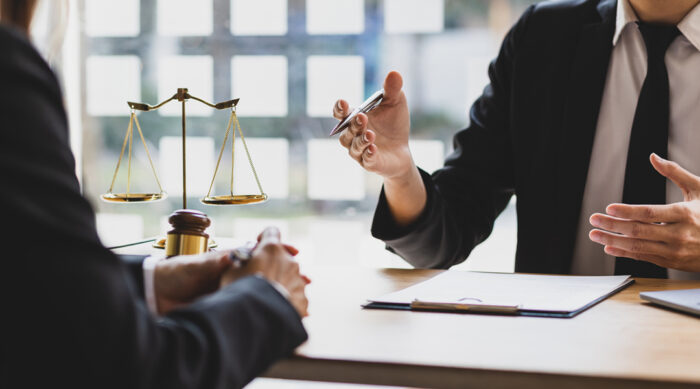 Two male defamation attorneys sit at a desk and discuss the timeline of how long lawsuits take.
