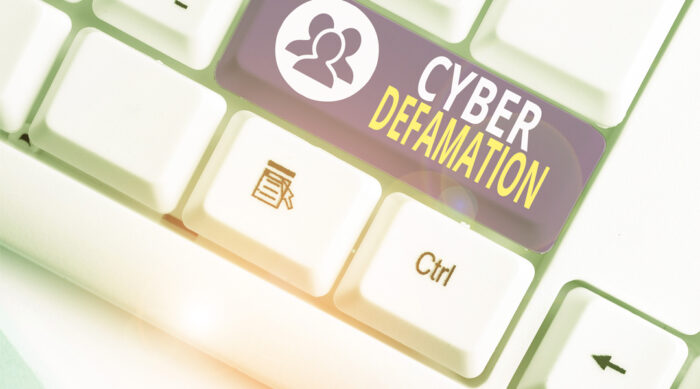 Computer keyboard with a large gray cyber defamation button.