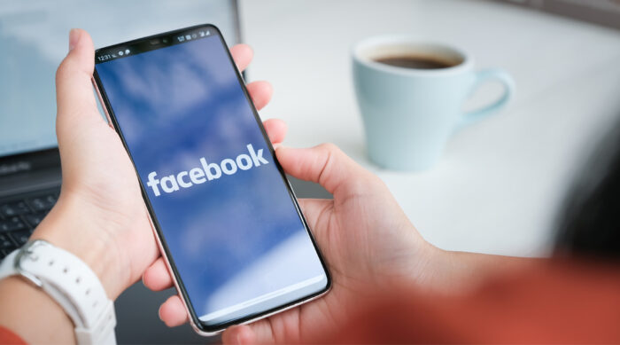Business owner logs into their Facebook business page on a smartphone to manage online reviews.
