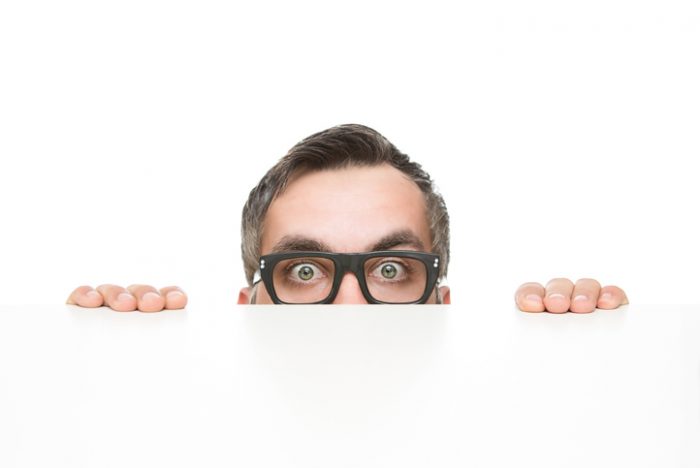 Guy peeking over the edge of a white desk