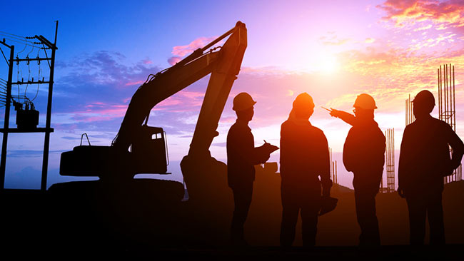 Construction workers against sunset with construction crane 