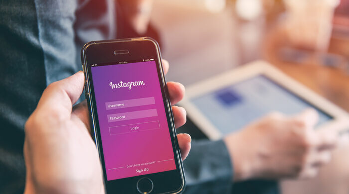 User holds an iPhone and attempts to log in to an Instagram account.