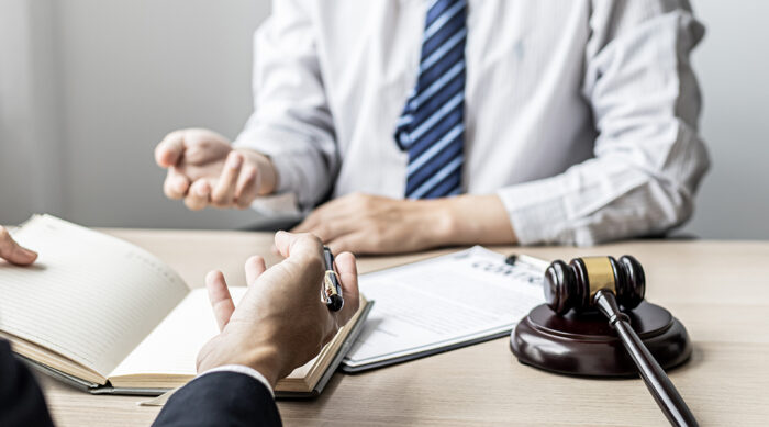 A male attorney sits with a client at a desk to discuss defamation per se.