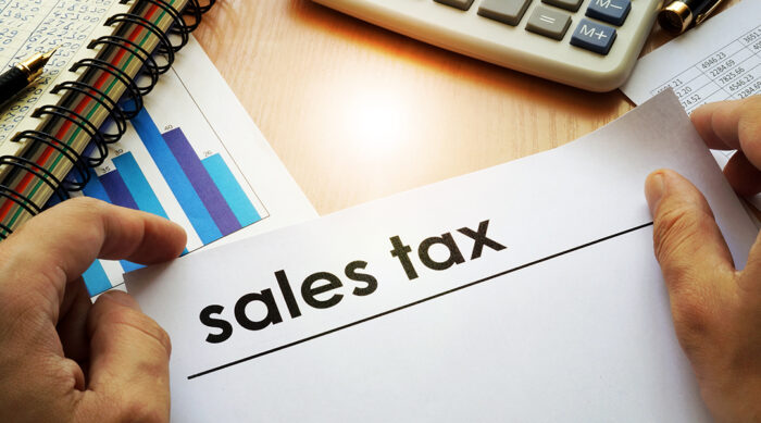A state and local tax lawyer holds a white sales tax document over a wooden desk.