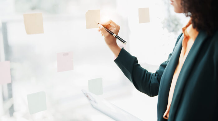 A female defamation attorney places notes on a large window and writes notes to support a defamation case.
